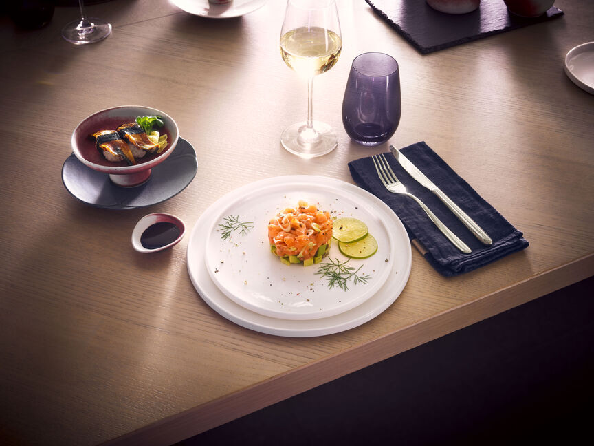 Tavola apparecchiata con stoviglie in gres di Rosenthal: antipasto su piatto bianco, zuppa in scodella, accompagnata da vino, posate e tovagliolo di stoffa.