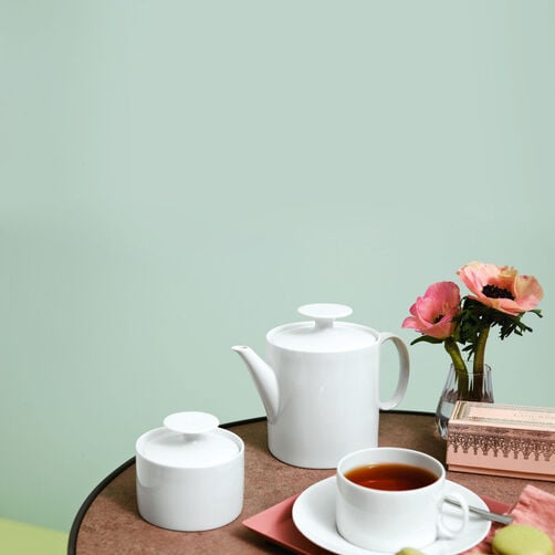 Thomas Medaillon Thomas Medaillon tea pot, sugar bowl, tea cup filled with tea on a small table on light green wall