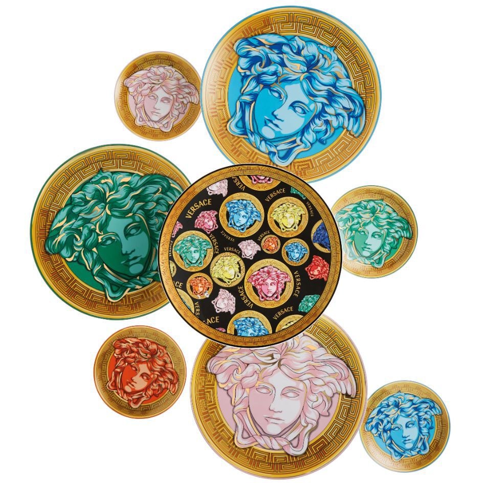Pop-art inspired Medusa Amplified plate set from Versace, featuring colorful Medusa heads on black and golden backgrounds in a bold, artistic arrangement.