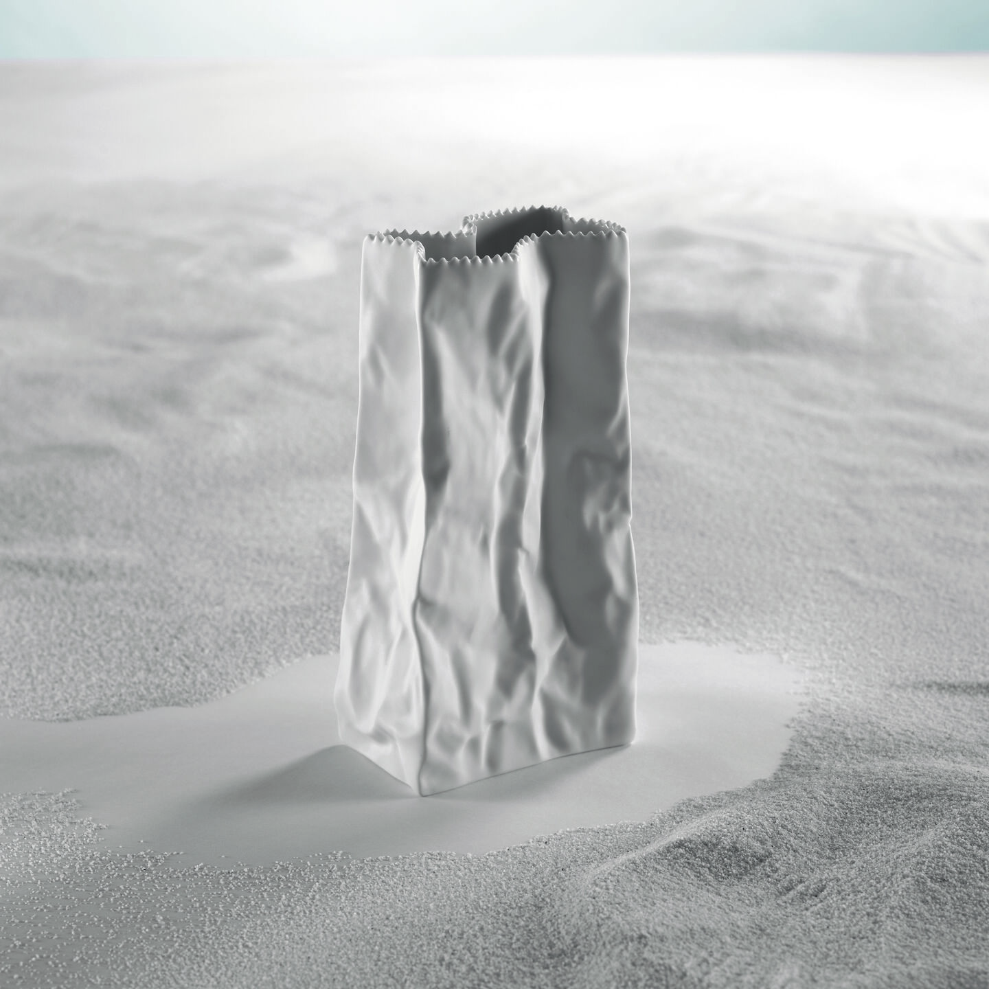 Rosenthal cone vase by Tapio Wirkkala against a white background with sand