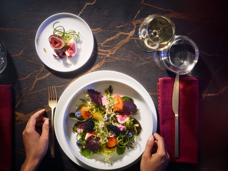 Draufsicht auf elegant gedeckten Tisch mit Bone China Porzellan von Rosenthal: Kunstvoll angerichtete Speisen auf feinen wei&szlig;en Tellern schaffen ein stilvolles Fine-Dining-Erlebnis.
