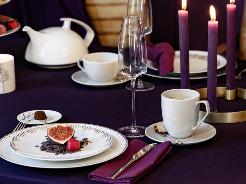 Tac Coffe cups in white on a purple tablecloth and fitting plates