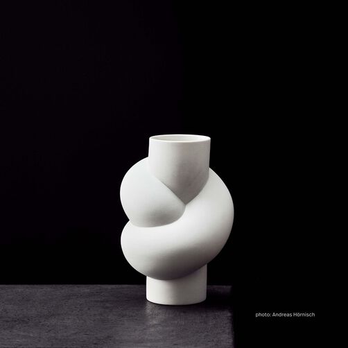 Node White on a dark grey concrete table against a black background.