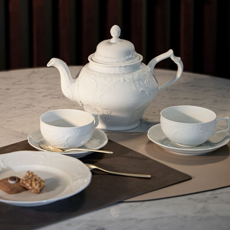 A classic porcelain set with ivory plates, gold trim, and teapot