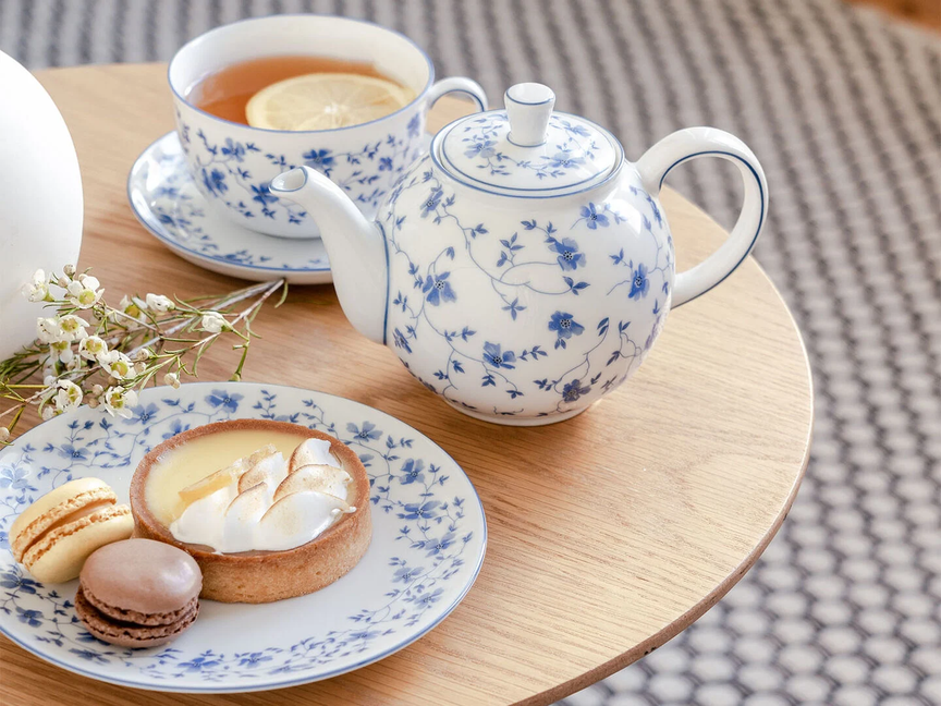 Rosenthal-Teeservice aus der Serie „Form 1382 Blaublüten“ mit zartem blauen Blütendekor, serviert mit Tee, Tartlette und Macarons.