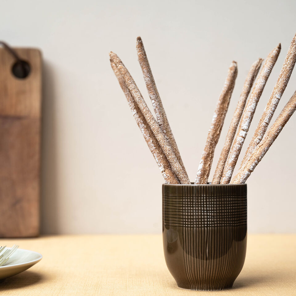 Il preferito di tutti i giorni, senza complicazioni Vista laterale di una tazza MUCA in legno, riempita di Grissini.