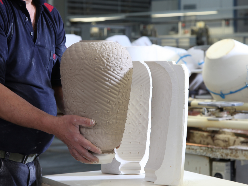 Porzellanherstellung: Ein Mitarbeiter entnimmt in einer Werkstatt ein ungebranntes, strukturiertes Gef&auml;&szlig; aus einer zweiteiligen Gussform.