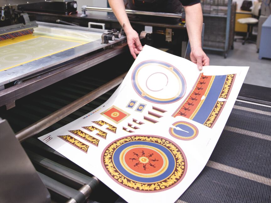 Porzellandekoration: Bedruckte Dekorfolien mit farbigen Mustern und Ornamenten werden f&uuml;r die &Uuml;bertragung auf Porzellan vorbereitet.