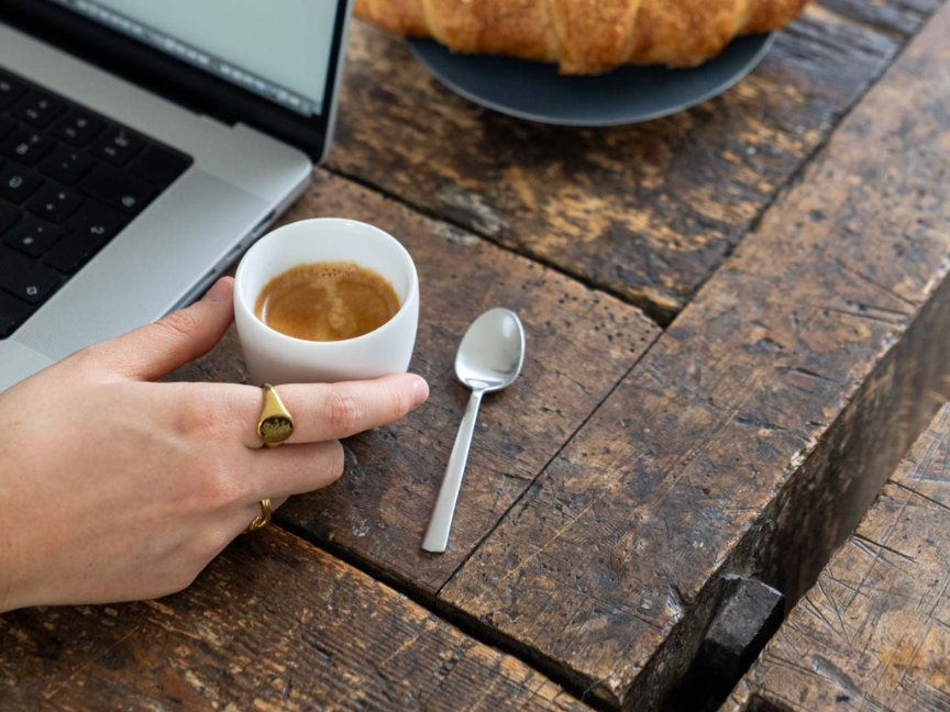Tasse &agrave; espresso Rosenthal de forme cylindrique compacte avec une petite anse finement travaill&eacute;e et une soucoupe assortie, remplie d'espresso et pos&eacute;e sur une table en bois rustique.