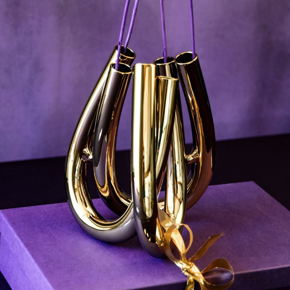 A metallic gold vase, arranged on a violet gift box.