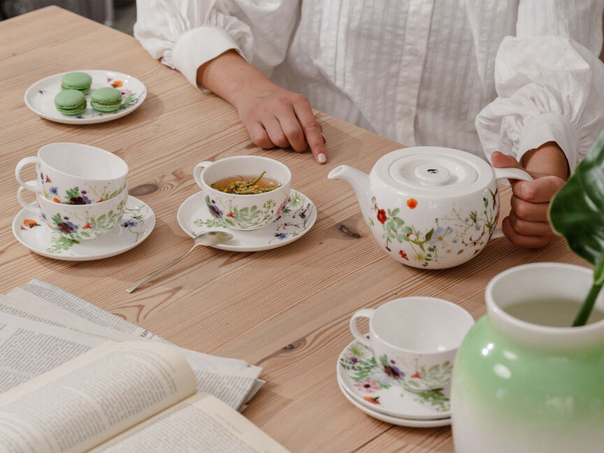 Colazione di primavera con Brillance Grand Air Vista dall'alto del piatto da pane e del piatto da colazione Brillance Grand Air, decorati con erbe e fiori di campo e una piccola ciotola con zucchero su un tavolo di legno.