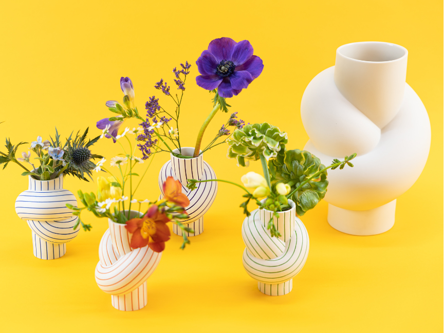 Bunte Blumen in gestreiften Rosenthal Vasen auf gelbem Hintergrund