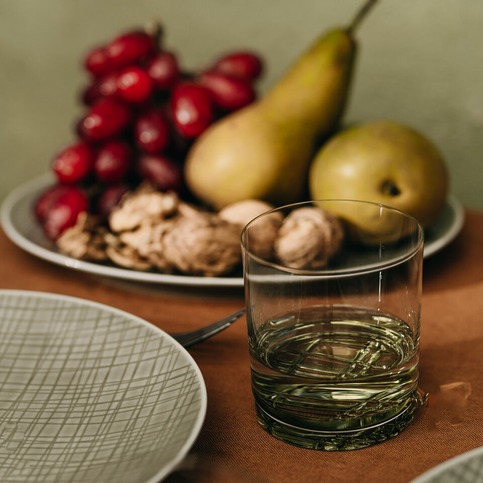 Raffinierte Linienstruktur Nahaufnahme eines Mesh Glasses und eines Mesh Tellers, im Hintergrund ein Obstteller.