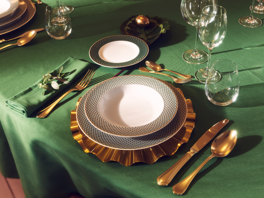 Prunkvoll gedeckter Tisch mit grün-goldenem Rosenthal-Geschirr, goldfarbenem Besteck, grüner Stoffserviette und edlem Platzteller auf grüner Tischdecke