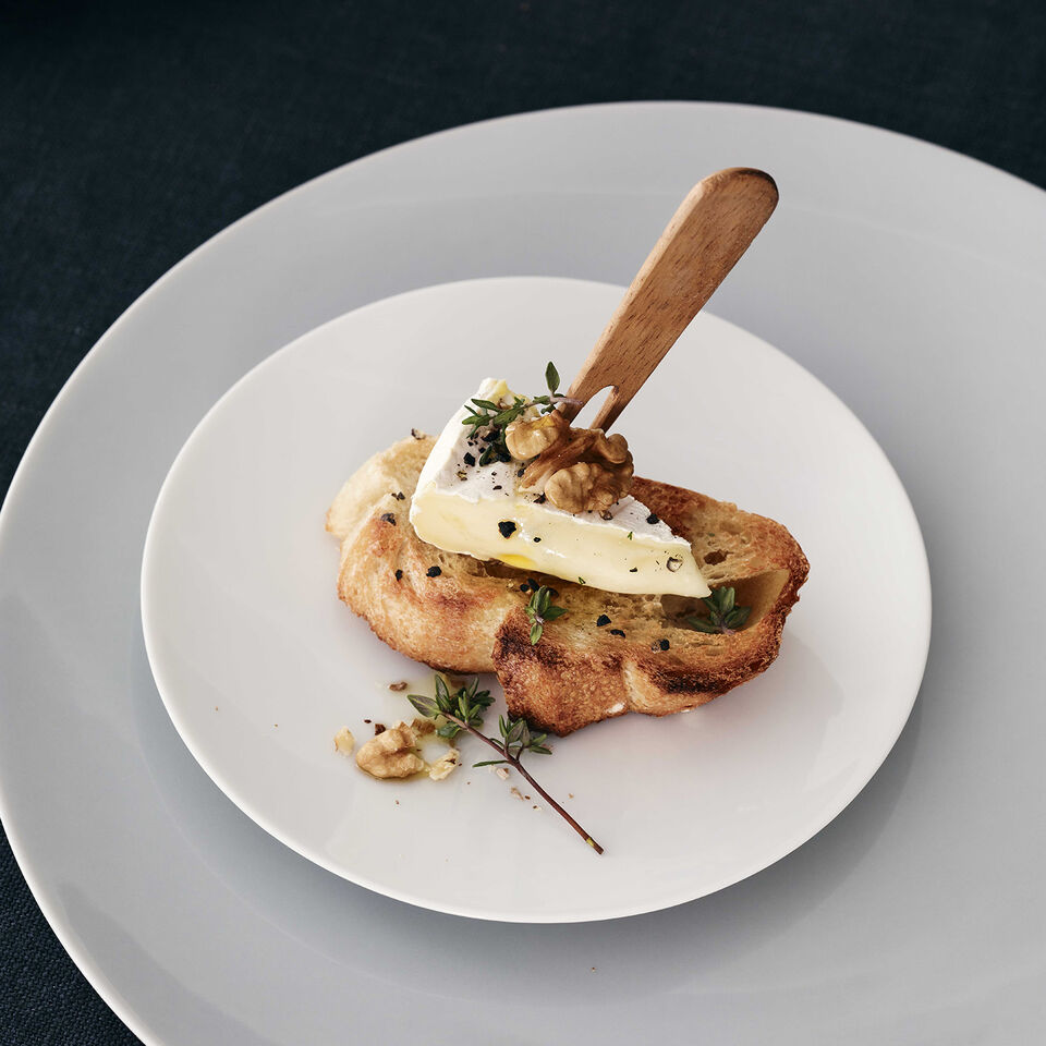 TAC Sensual Gentle Grey Close-up of a TAC White bread plate garnished with baguette, cheese and walnuts, standing on a large TAC Sensual plate in Gentle Grey.
