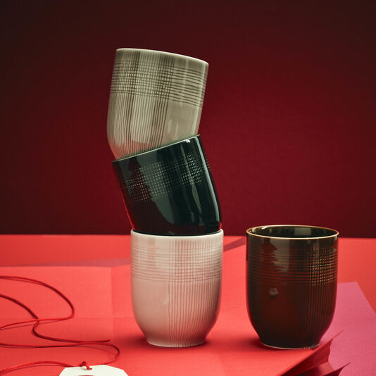 MUCA Becher ineinander gestapelt auf rotem Papier und vor dunkelrotem Hintergrund