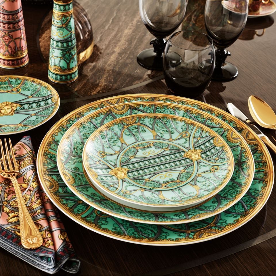 La Scala del Palazzo collection by Versace in vibrant mint green and gold, with baroque architectural motifs and black-stem glasses, creating an opulent tablescape.