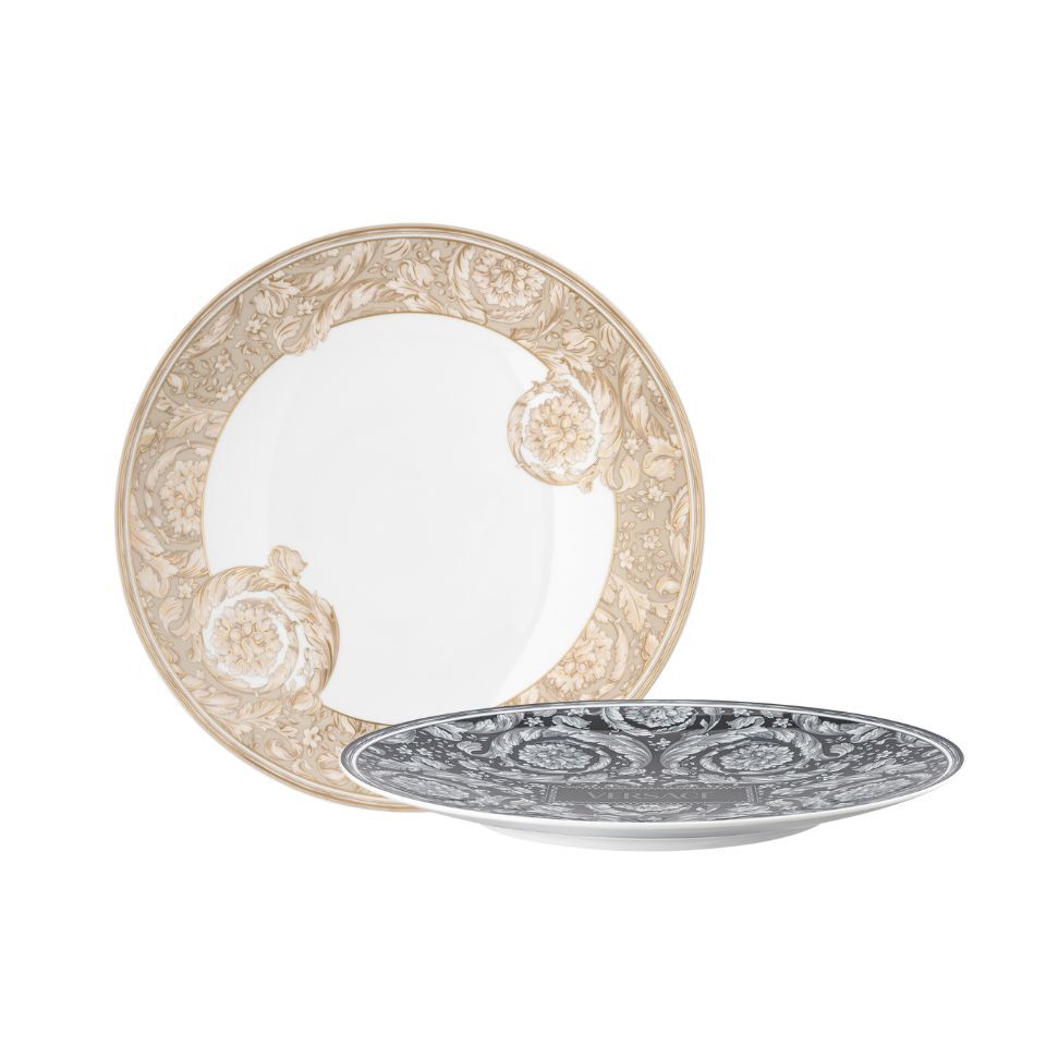 Two Versace porcelain plates with ornate floral baroque patterns, one in beige and gold tones and the other in black and silver, displayed on a white background.