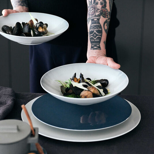 Serving made easy with TAC A person with tattoos on their arm serves a seafood dish with the relief soup plate from TAC Sensual.