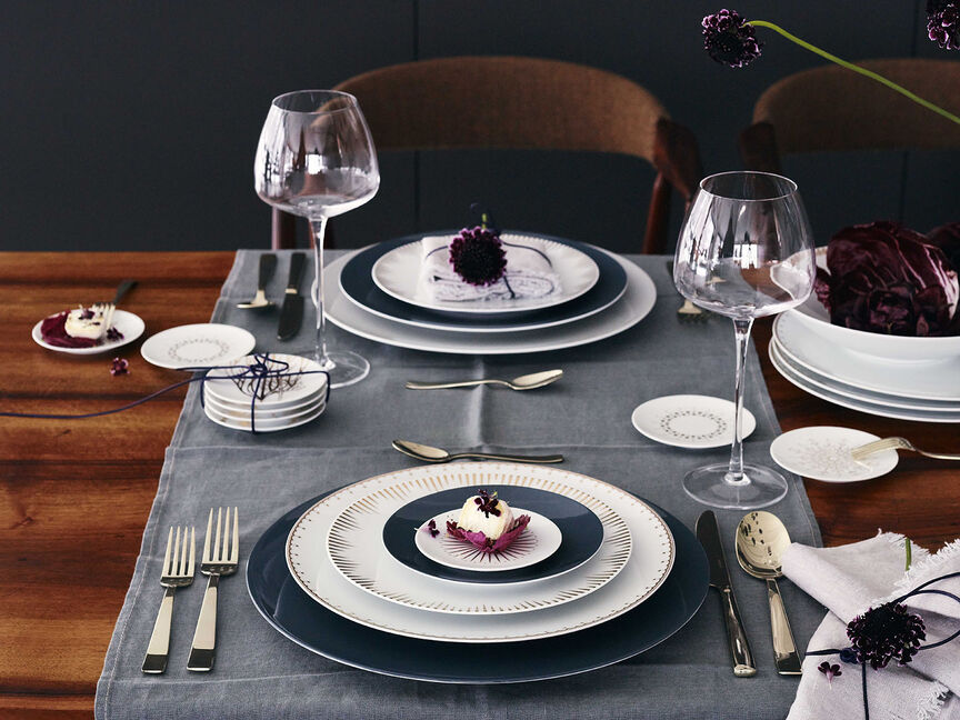 Festive mood with TAC Wooden table set with TAC Sensual and TAC Festive Celebration plates, cutlery, wine glasses and purple decorative elements.