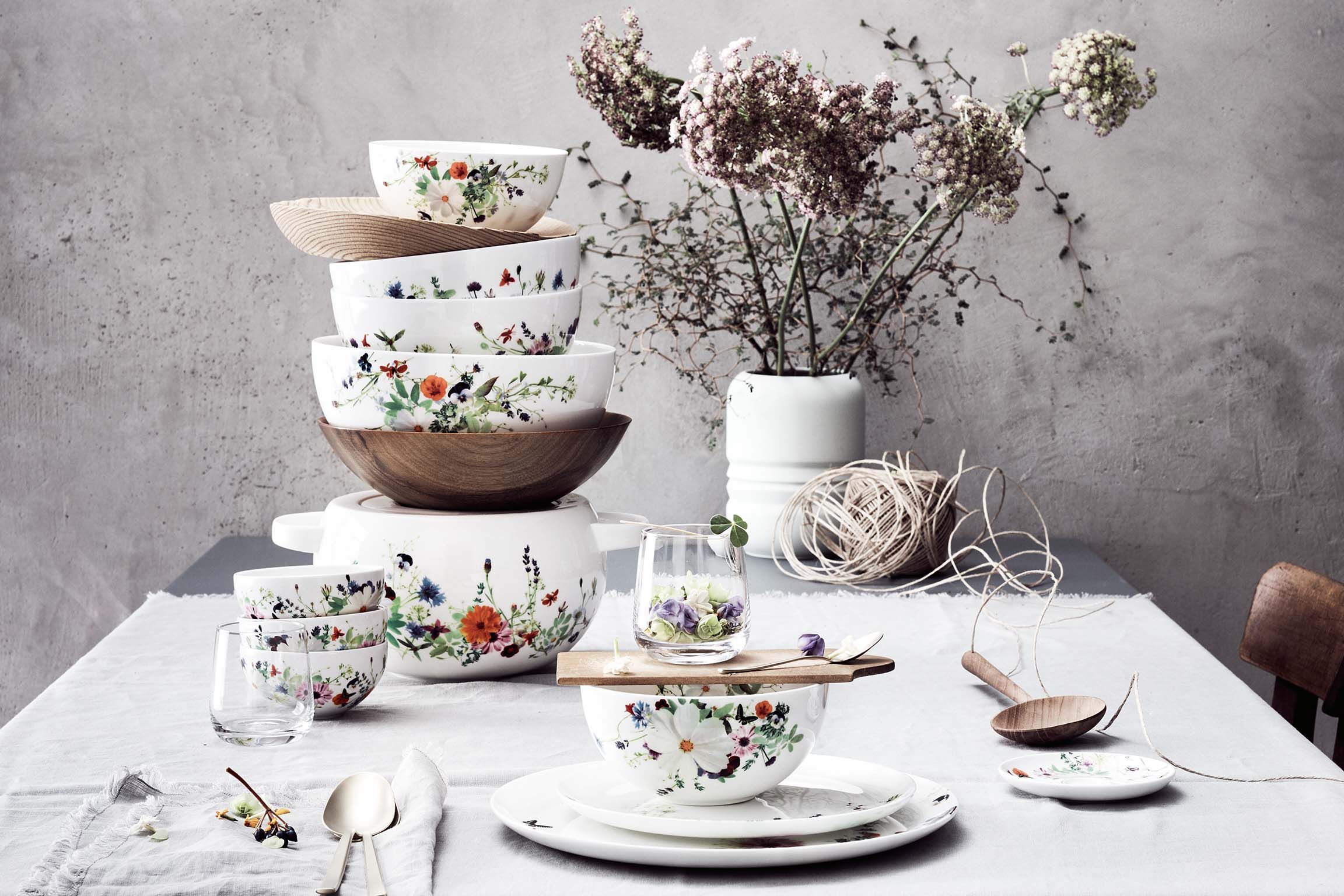 Unterschiedlich große Bowls der Brillance Grand Air Dining Collection auf einem mit weißer Leinendecke und mit Trockenblumen dekorierten Tisch.