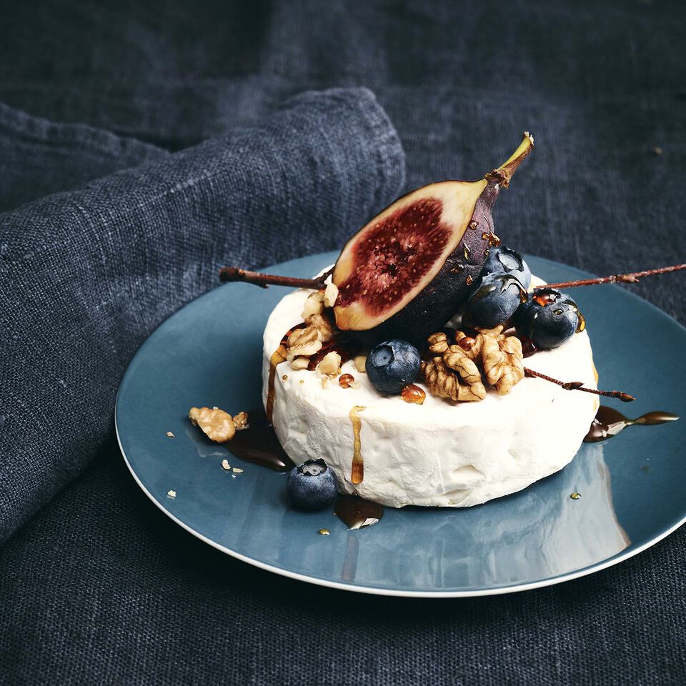 TAC Sensual Comfort Blue Close-up of a small TAC Sensual plate in Comfort Blue standing on a dark blue linen cover and garnished with camembert, blueberries, walnuts and a fig.
