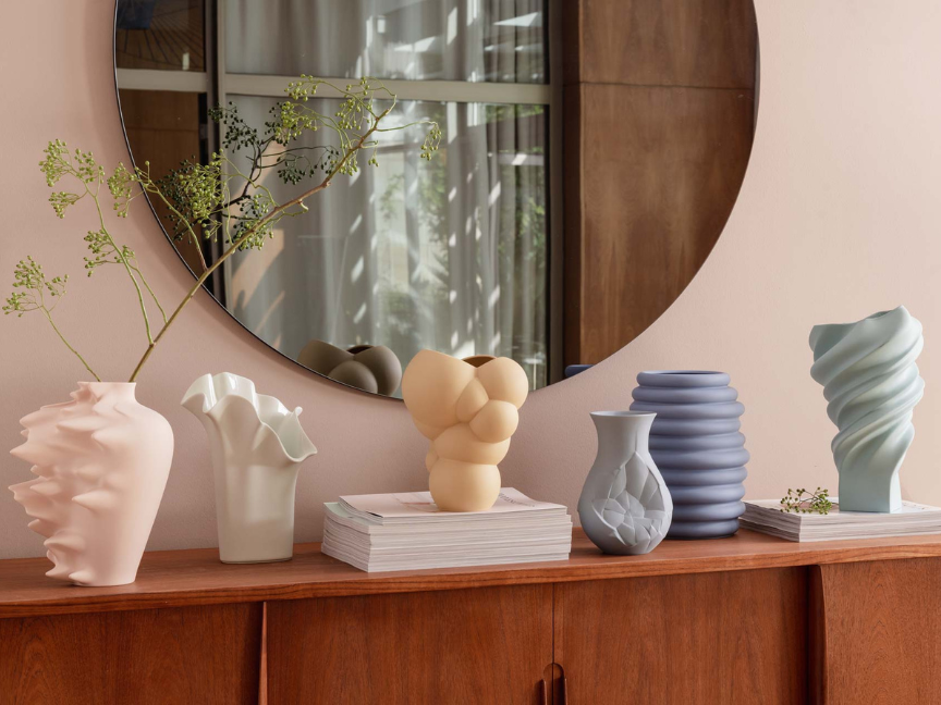 Rosenthal Designvasen auf Holzsideboard vor rundem Spiegel