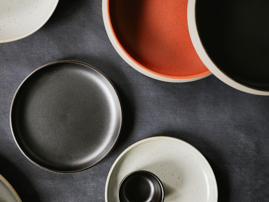 Rosenthal tableware in black, orange and beige, viewed from above against a dark grey background