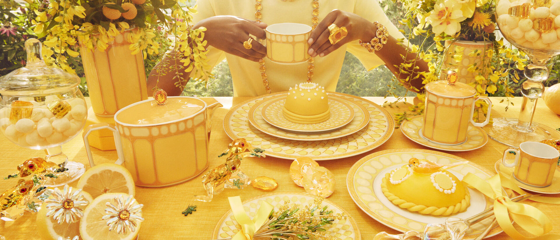 Extravagantes Rosenthal-Geschirr in Gelbt&ouml;nen auf kunstvoll dekorierter Tafel mit Teeservice, Tellern, Tassen und Desserts im luxuri&ouml;sen Fr&uuml;hlingsdesign.