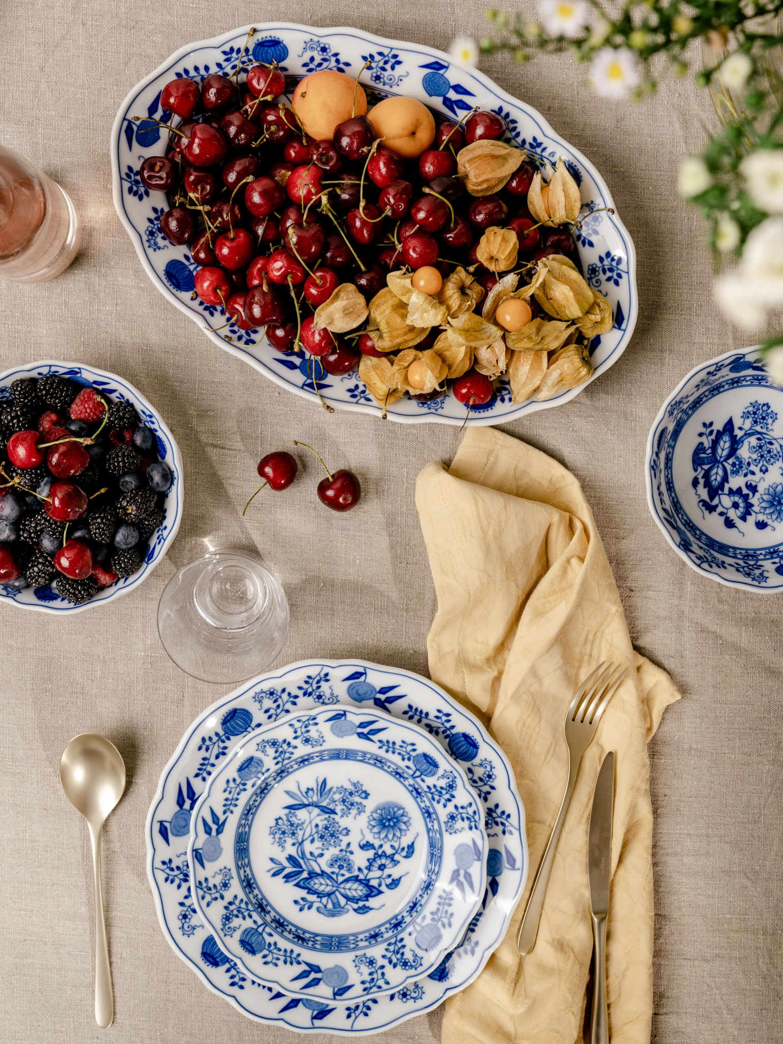 Hutschenreuther Blau Zwiebelmuster Platte voller Kirschen, darunter Teller mit goldenem Besteck