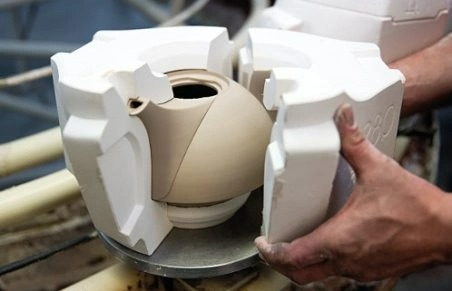 The plaster mould is removed by hand to reveal a teapot