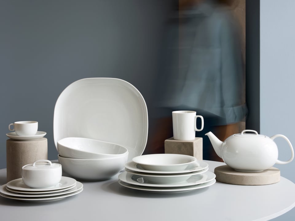 Different Plates, bowls, cups and a tea pot arranged on a table