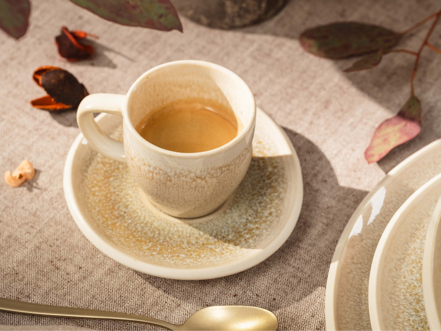 Beige Espressotasse auf grauer Tischdecke