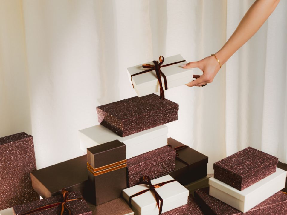 Hand legt Geschenkbox auf Stapel