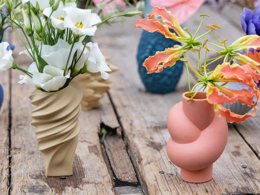 Moderne Rosenthal Vasen mit wei&szlig;en und orangen Bl&uuml;ten auf Holztisch
