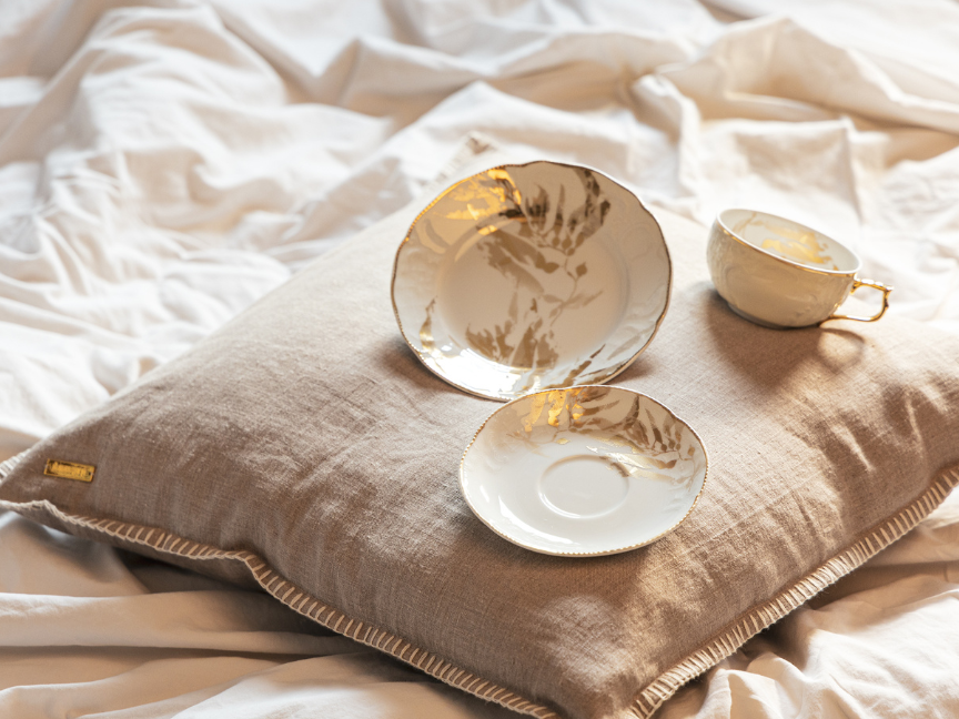 orzellan-Ensemble der Rosenthal-Kollektion Heritage Midas mit goldenen Akzenten, gestaltet von Designer Gianni Cinti, arrangiert auf einem Leinenkissen.
