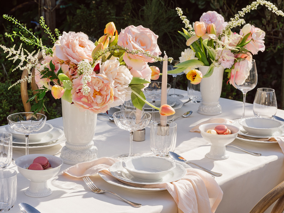 Floral table setting with vases filled with colourful flowers and plates with cutlery und glasses for 4 persons
