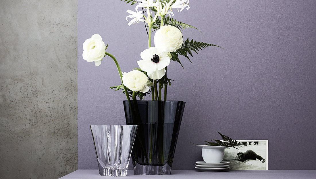 Zwei verschieden große Rosenthal Glasvasen mit weißen Blumen auf violettem Hintergrund